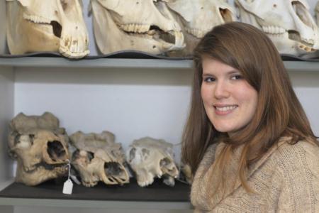 Suzanne Pilaar Birch stands in front of a shelf holding animal skulls